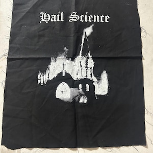 Puede incluir: Parche de tela negra con las palabras "Hail Science" en fuente gótica blanca sobre una ilustración blanca de una iglesia. Un rectángulo negro en la parte inferior muestra "veganpatches.com".