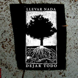 May include: Black and white patch with a tree and a skeleton lying beneath it. The text "Llevar Nada" is above the tree and "Dejar Todo" is below the tree.
