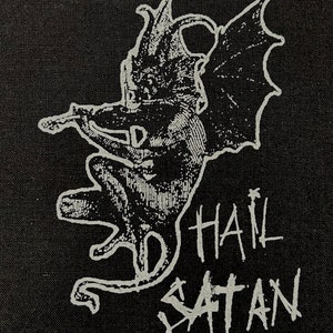 May include: Black and white patch featuring a winged demon figure and the text "Hail Satan" in white.