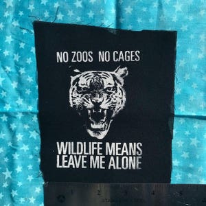 Könnte beinhalten: Schwarz-weißes Patch mit einer Tigerillustration und dem Text "No zoos no cages Wildlife means leave me alone".