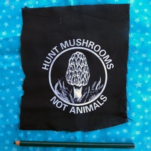 Könnte beinhalten: Schwarzer Stoff-Patch mit weißem Text und einer Grafik eines Morchel-Pilzes. Der Text lautet "Hunt Mushrooms Not Animals."