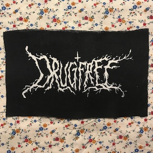 May include: Black fabric patch with white lettering that reads "DRUGFREE" in a stylized font.