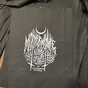 May include: Black patch with white text and a graphic design. The text reads "MY ALLEGIANCE IS TOTAL" and the graphic design is a stylized logo with the word "MONOCHROME" in it.
