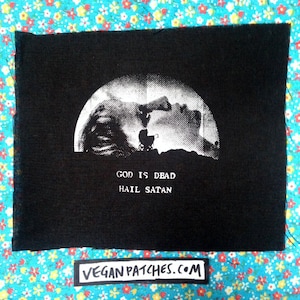 May include: Black and white iron-on patch with a graphic of a woman's face and a baby carriage in front of a moon. The text "God is Dead Hail Satan" is printed below the graphic.