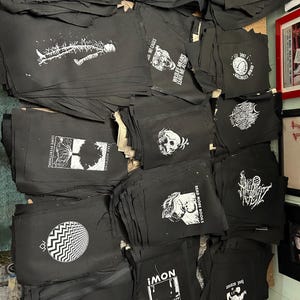 May include: A stack of black fabric patches with white text and images. The patches feature various slogans and designs, including "Rescue Dog", "Fur is for Animals, Not Rich Idiots", "Wildlife Means Leave Me Alone", "Read More Books", "Police Accountability", and "Carrie".