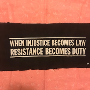 May include: Black fabric patch with white text that reads "When injustice becomes law resistance becomes duty."
