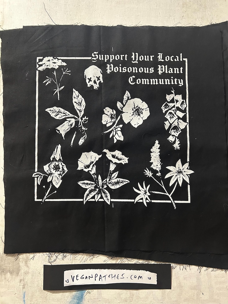 May include: Black fabric patch with a white graphic of various plants, a skull, and the text "Support Your Local Poisonous Plant Community." A smaller rectangle at the bottom reads "veganpatches.com."