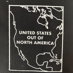 Puede incluir: Un cuadrado negro con un contorno blanco de América del Norte. El texto "UNITED STATES OUT OF NORTH AMERICA" está centrado dentro del contorno. La imagen es una representación gráfica simple de la ubicación de los Estados Unidos.