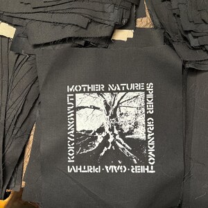 May include: Black and white patch with the text "MOTHER NATURE'S SPIDER GRANDMOTHER", "THIEVES. VIVA. WHIRLWIND", and "KOKYANGVULT" printed on it. The patch features a black and white image of a tree with roots.