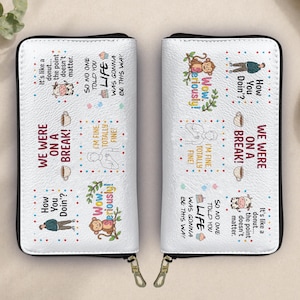 Pode incluir: Carteira branca dobrável com zíper preto e puxadores dourados. A carteira apresenta várias ilustrações de desenhos animados e texto, incluindo frases como "We were on a break!" e "How you doin'?"