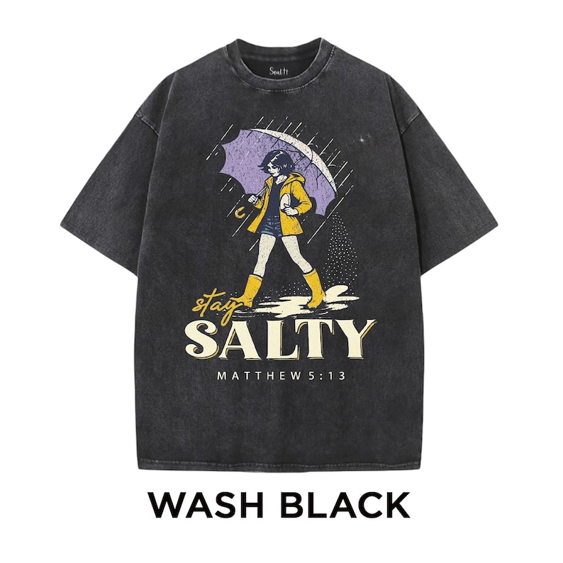 May include: Wash black t-shirt with a graphic of a person walking in the rain under an umbrella. The person is wearing a yellow jacket and boots. The text "stay SALTY" and "MATTHEW 5:13" are below the graphic.