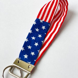 Peut inclure: Un porte-clés en forme de drapeau américain rouge, blanc et bleu avec un anneau de clé argenté.