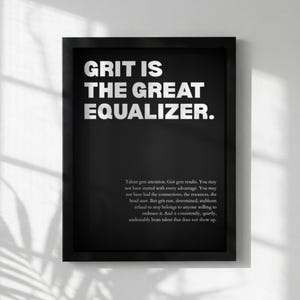 May include: Black framed print with white text reading "GRIT IS THE GREAT EQUALIZER." A paragraph of text is below the main text. The print is mounted on a white wall.