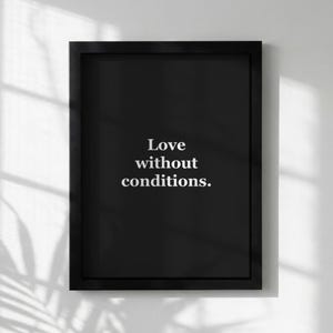 May include: A framed black print featuring the white text "Love without conditions" centered on a black background. The frame is a simple, rectangular design. The print is displayed against a white wall.