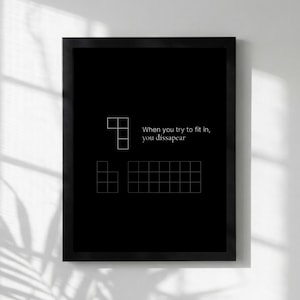 Könnte beinhalten: Ein gerahmter schwarzer Druck mit weißen geometrischen Formen und dem Text: „When you try to fit in, you disappear.“ Das Kunstwerk zeigt Tetris-ähnliche Blockanordnungen, die eine Botschaft über Individualität und Konformität vermitteln.