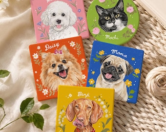 Op de afbeelding: Vijf vierkante en ronde onderzetters met aangepaste huisdierportretten. De roze onderzetter toont een witte hond genaamd Harvey, de groene ronde een zwart-witte kat genaamd Mochi, de oranje een bruine hond genaamd Daisy, de blauwe een mopshond genaamd Mama en de gele een bruine hond genaamd Benji.