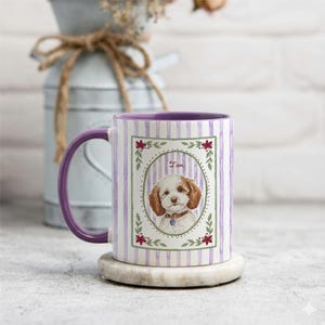 Puede incluir: Una taza de cer&aacute;mica con asa e interior de color morado, con un patr&oacute;n de rayas verticales de color morado claro. El centro muestra un marco ovalado con hojas verdes y flores rojas, que encierra una ilustraci&oacute;n en acuarela de un perro y el nombre Tom.