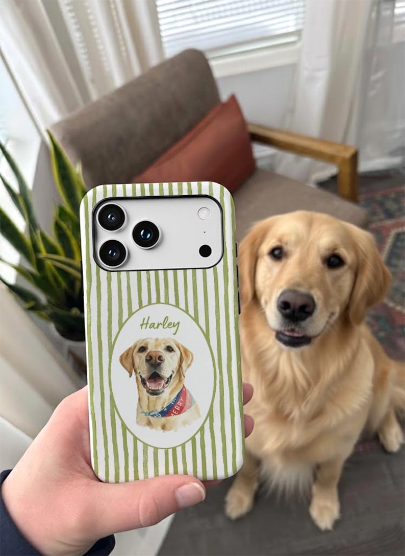 Op de afbeelding: Een smartphonehoesje met een verticaal gestreept patroon in olijfgroen en wit. In het midden bevindt zich een ovaal kader met een aquarelillustratie van een golden retriever met een blauwe bandana, met daarboven de naam Harley gedrukt.