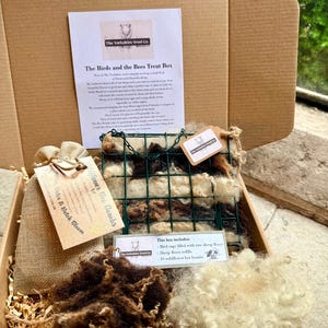 May include: A cardboard gift box containing a green wire bird feeder filled with raw sheep fleece, a hessian drawstring bag, two loose piles of brown and white raw sheep fleece, and informational cards titled The Birds and the Bees Treat Box.