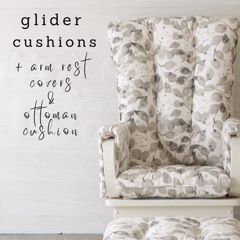 May include: White glider with a gray and white leaf patterned cushion, arm rests, and ottoman. The text "glider cushions + arm rest covers & ottoman cushion" is written on the wall behind the glider.