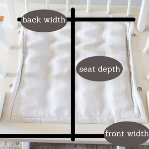 Puede incluir: Silla mecedora blanca con un coj&iacute;n de asiento de tela blanca. El coj&iacute;n del asiento est&aacute; etiquetado con medidas para el ancho del respaldo, la profundidad del asiento y el ancho del frente.