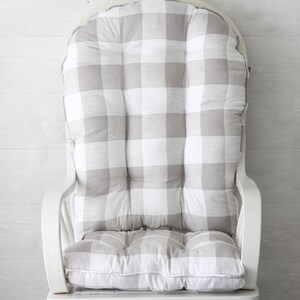 Puede incluir: Un coj&iacute;n para mecedora de gingham blanco y gris con dise&ntilde;o capiton&eacute;.