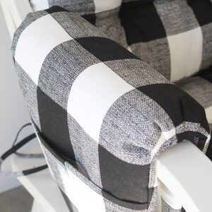 May include: Black and white buffalo check armrest cushion with a pocket. The cushion is made of a soft, textured fabric and has a white background with black squares.