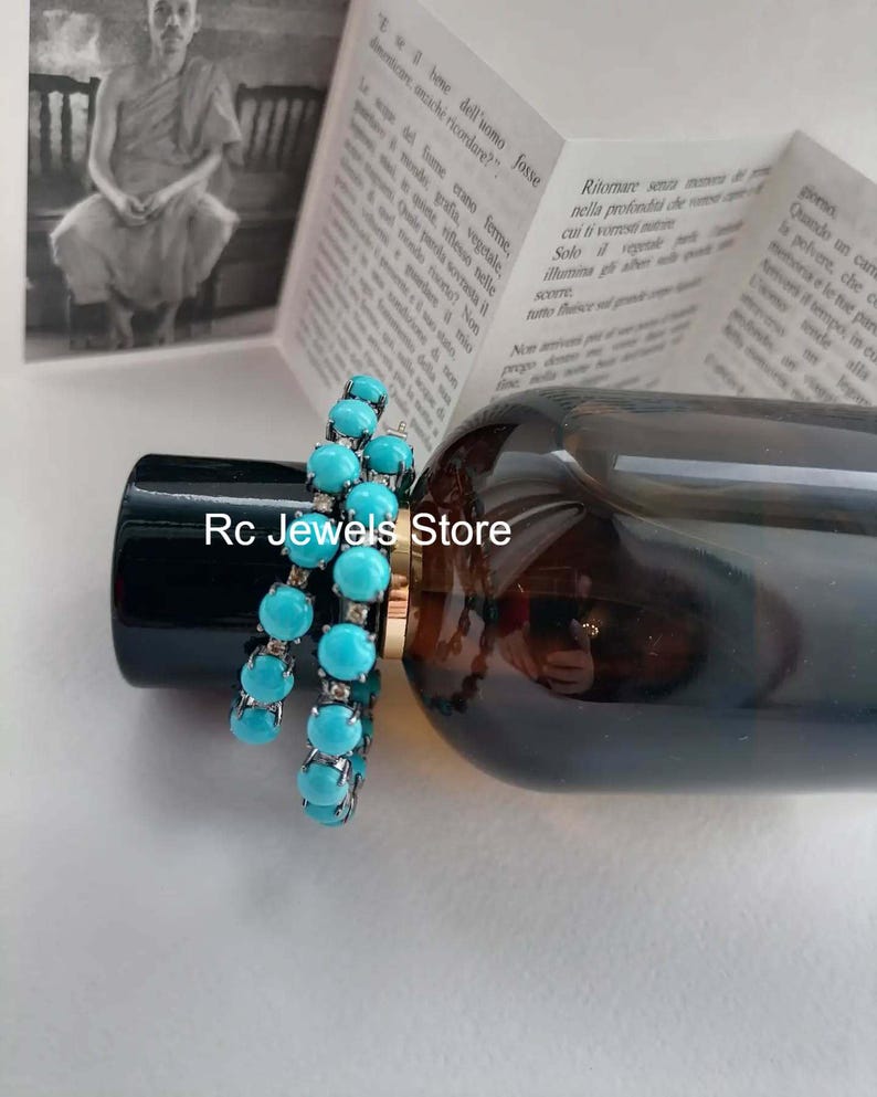 May include: Two turquoise beaded bracelets are displayed on a dark bottle. The bracelets feature round, light blue beads and silver-colored metal. The text "Rc Jewels Store" is visible on the bottle.