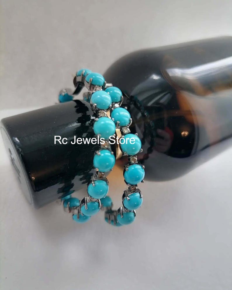 May include: A pair of turquoise bead bracelets with silver-colored settings. The bracelets are wrapped around a dark bottle. The text "Rc Jewels Store" is visible on the bottle.