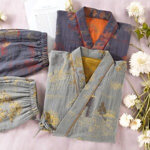 May include: A gray kimono-style robe with a landscape design in gold and brown, paired with matching pants. The robe has a V-neck and a tie closure. The second robe is gray with orange and red accents.