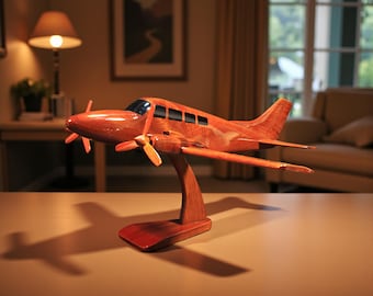Könnte beinhalten: Ein Holzmodellflugzeug mit rotbraunem Finish. Das Modell verfügt über zwei Propeller, Flügel und ein Heck, montiert auf einem Holzständer. Das Flugzeug hat ein detailliertes Design mit sichtbaren Fenstern und steht auf einem Tisch.