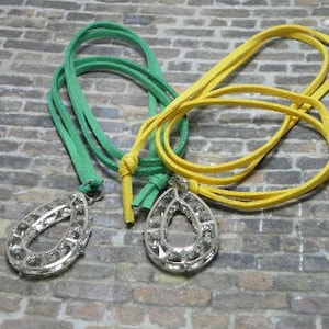 May include: Two necklaces with teardrop-shaped pendants featuring clear rhinestones. One necklace has a green cord and the other has a yellow cord.