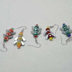 May include: Five pairs of earrings with geometric shapes and colorful beads. The earrings are made of silver metal and feature a variety of colors, including red, green, blue, and yellow.