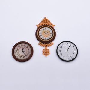 Puede incluir: Tres relojes sobre un fondo blanco. Uno es redondo con esfera negra y números blancos. Dos son marrones con números romanos, uno redondo y otro con detalles ornamentados.