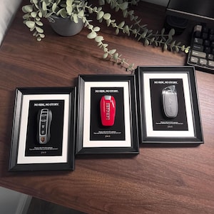 May include: Three framed prints featuring car keys against a black background. Each print has a white border and a black frame. The text "NO RISK, NO STORY" is at the top of each print. The keys are from Porsche, Ferrari, and Lamborghini.