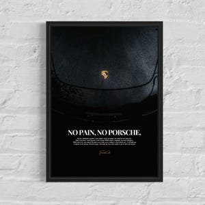 May include: Black framed poster with a close-up of a black Porsche car, displaying the Porsche emblem. The poster includes the white text "NO PAIN, NO PORSCHE", a quote, and a signature. The car's surface shows water droplets.