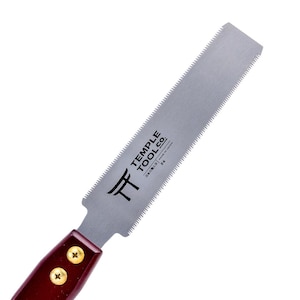 Könnte beinhalten: Japanische Zugsäge mit silberner Klinge und dunkelrotem Holzgriff. Die Klinge hat feine Zähne und der Text "TEMPLE TOOL CO." ist auf der Klinge aufgedruckt.