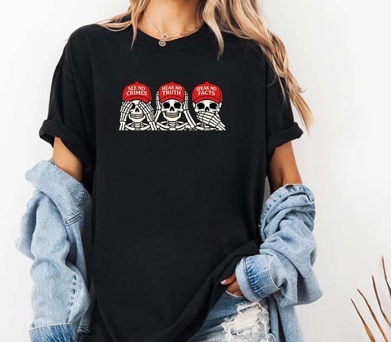 May include: Black t-shirt featuring a graphic of three skeleton figures, each with hands covering their eyes, ears, and mouth. The skeletons wear red caps with the phrases "SEE NO CRIMES", "HEAR NO TRUTH", and "SPEAK NO FACTS".