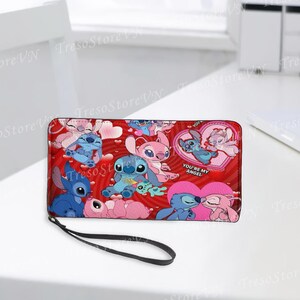 Puede incluir: Cartera roja con los personajes de dibujos animados Stitch y Angel, corazones y el texto "YOU'RE MY ANGEL". La cartera tiene una correa de mu&ntilde;eca negra. El dise&ntilde;o presenta varias poses de los personajes.