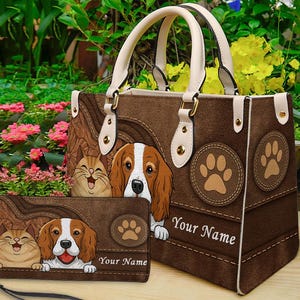 May include: A brown handbag and matching wallet with a beagle and a cat design. The bag has cream-coloured handles and paw print accents. The text "Your Name" is displayed on both items. The bag and wallet are made of a suede-like material.