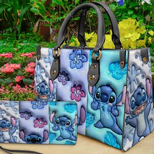 K&ouml;nnte beinhalten: Ein blau-wei&szlig;es Shopper-Taschen- und passendes Geldb&ouml;rsen-Set. Die Tasche hat ein Cartoon-Charakter-Design mit blauen und rosa floralen Akzenten. Die Geldb&ouml;rse hat eine Handschlaufe. Das Set ist aus Kunstleder.