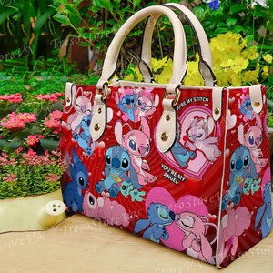 Puede incluir: Bolso tote rojo con personajes de dibujos animados, corazones y el texto "You're My Angel". El bolso tiene asas y detalles en color crema. El bolso est&aacute; decorado con im&aacute;genes de Stitch y Angel.