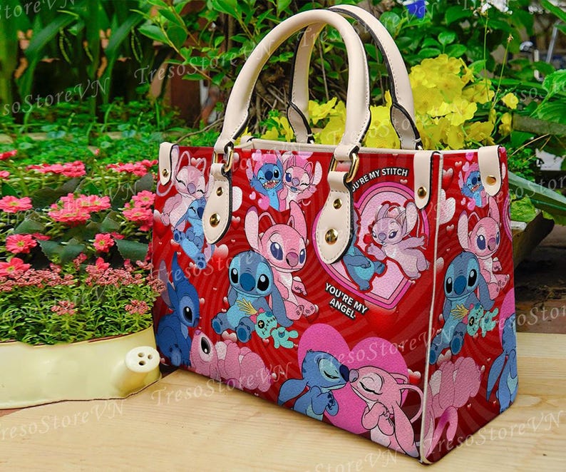Puede incluir: Bolso tote rojo con personajes de dibujos animados, corazones y el texto "You're My Angel". El bolso tiene asas y detalles en color crema. El bolso est&aacute; decorado con im&aacute;genes de Stitch y Angel.