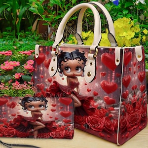 May include: A handbag and matching wallet set featuring a cartoon character in a red dress, surrounded by red hearts and roses. The handbag has cream-colored handles and trim. The wallet has a black strap.