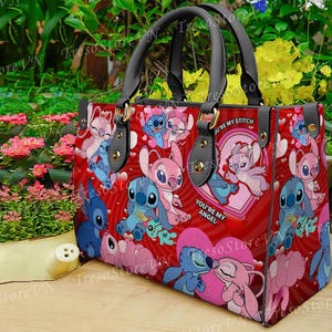 Puede incluir: Un bolso de mano rojo con un patr&oacute;n repetido de personajes de dibujos animados, corazones y las frases "You're my Stitch" y "You're my Angel". El bolso tiene asas y detalles en negro.
