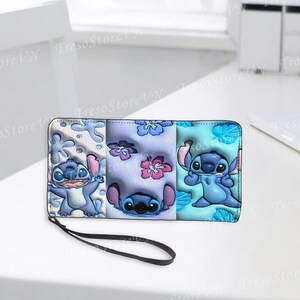 K&ouml;nnte beinhalten: Ein dreifach gefaltetes Portemonnaie mit einer schwarzen Handschlaufe, das die Figur Stitch aus Lilo & Stitch zeigt. Das Portemonnaie ist in drei Abschnitte unterteilt, jeder mit einem anderen Stitch-Design und floralen Mustern in Blau, Rosa und Wei&szlig;.