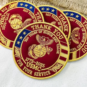 May include: Circular red and gold embroidered patches with the text "THANK YOU FOR YOUR SERVICE" and "250 YEARS OF HONOR AND VALOR". The patches feature the USMC emblem and the years 1775-2025.