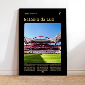 Könnte beinhalten: Schwarzes Poster mit dem Estádio da Luz Stadion in Lissabon, Portugal. Das Bild zeigt das Innere des Stadions mit roten Sitzen und einem grünen Spielfeld unter blauem Himmel. Text enthält "Estádio da Luz" und Standortdetails.