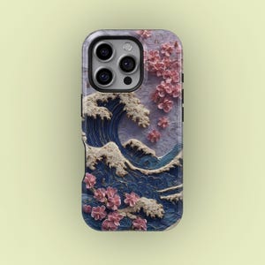 May include: A phone case featuring a Japanese-inspired design. The case showcases a stylized ocean wave in shades of blue and white, with pink cherry blossoms. The case has a glossy finish and a black border.