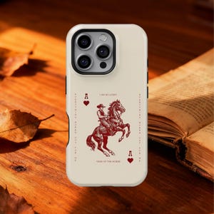 May include: A cream phone case with a red illustration of a cowboy on a rearing horse, with the text "I AM SO LUCKY" and "YEAR OF THE HORSE." The design includes playing card symbols and the phrase "EVERYTHING WORKS OUT FOR ME."